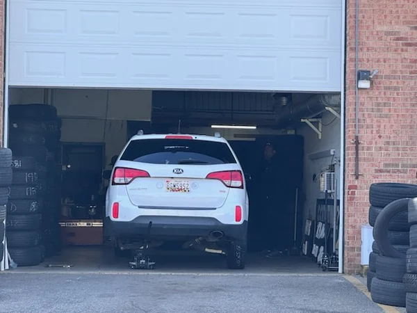 The interior of a workshop bay with a car on the floor, tire stacks and equipment along the wall.