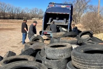 Scrap tires being loaded onto a flatbed truck from a lot.