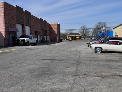 A row of brick units seen from along the parking lot, showing the approach to the shop.